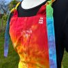 pinafore dress tie dyed in a rainbow colourway with red, orange, yellow, green, turquoise and purple.