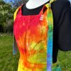 pinafore dress tie dyed in a rainbow colourway with red, orange, yellow, green, turquoise and purple.