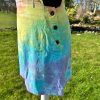 pinafore dress tie dyed in a pale rainbow colourway with pastel pink, orange, yellow, green, turquoise and purple.