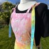 pinafore dress tie dyed in a pale rainbow colourway with pastel pink, orange, yellow, green, turquoise and purple.