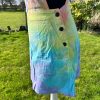 pinafore dress tie dyed in a pale rainbow colourway with pastel pink, orange, yellow, green, turquoise and purple.