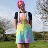 pinafore dress tie dyed in a pale rainbow colourway with pastel pink, orange, yellow, green, turquoise and purple.