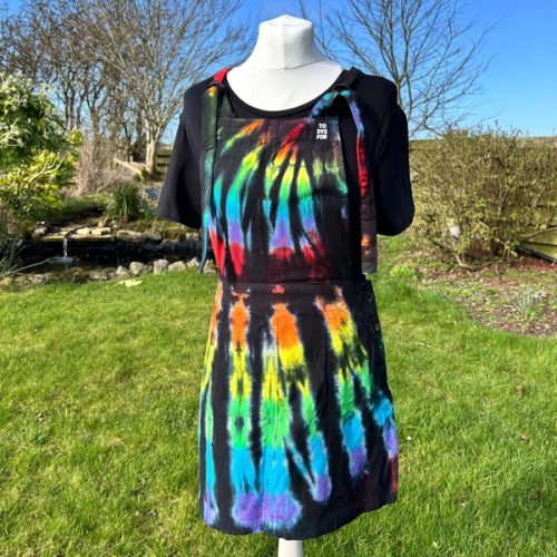 pinafore dress tie dyed in a black rainbow colourway with red, orange, yellow, green, turquoise and purple slashed through with black