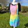 pinafore dress tie dyed in a pale rainbow colourway with pastel pink, orange, yellow, green, turquoise and purple.