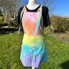 pinafore dress tie dyed in a pale rainbow colourway with pastel pink, orange, yellow, green, turquoise and purple.