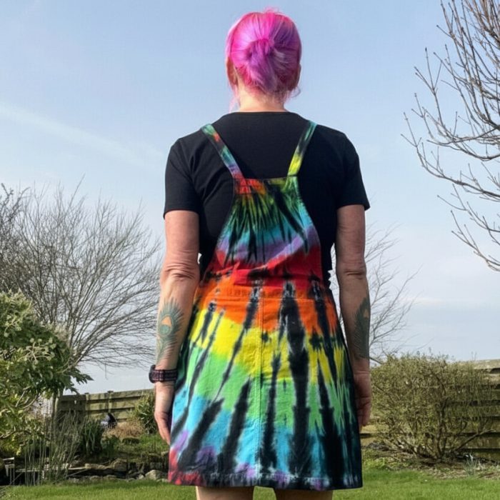 pinafore dress tie dyed in a black rainbow colourway with red, orange, yellow, green, turquoise and purple slashed through with black