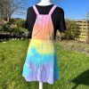 pinafore dress tie dyed in a pale rainbow colourway with pastel pink, orange, yellow, green, turquoise and purple.